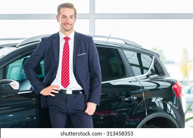 Seller Or Car Salesman In Car Dealership Presenting His New And Used Cars In The Showroom