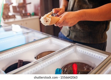 Seller Filling Waffle Cone With Ice-cream. Vanilla Flavour With Cookies Crumbs