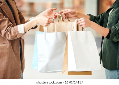 Seller giving paper bags of packed goods to woman and thanking her for shopping