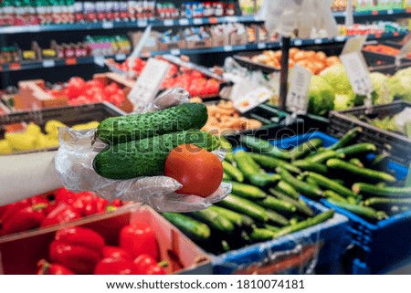 seller in gloves sells fresh vegetables. man gives dollars for groceries in the supermarket. covid19