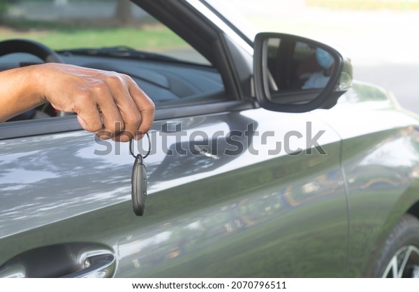 Seller is handing over a key\
remote control to buyer from inside the car at showroom on delivery\
day.