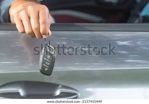 Seller is handing over a key remote\
control to buyer from inside the car at showroom on delivery day\
after driving\
demonstration.