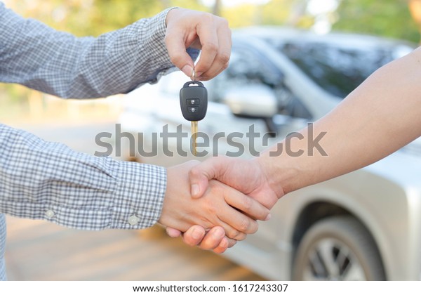 The seller hands over\
the keys to the buyer - auto business, car sale, deal, gesture and\
people concept 