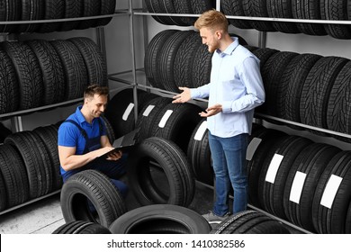 Seller helping man to choose tires in car store