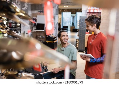 Seller Holding Digital Tablet Near African American Man Playing Electric Drums In Store