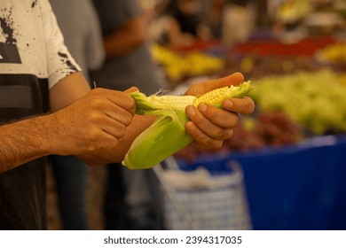 seller peeling corn in the market - Shutterstock ID 2394317035