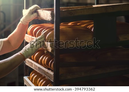 Seller puts  bread on  shelf. Fresh buns from the oven. Baking bread. Transportation of baking. Confectionery.