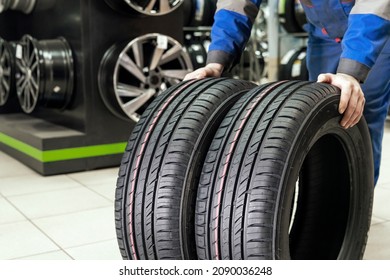 The Seller Rolls A Pair Of New Tires For The Season To The Store's Exit. Buying New Wheels - Road Safety