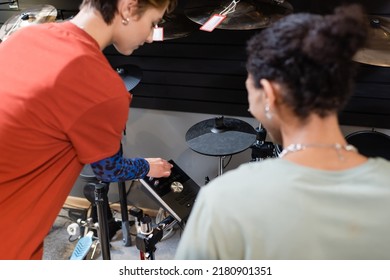Seller Standing Near Electronic Drum Set And African American Customer In Music Store