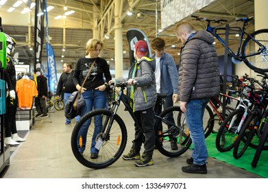Seller stands near bicycles showing them to customers. Bike Expo-2019. March 8, 2019. Kiev, Ukraine