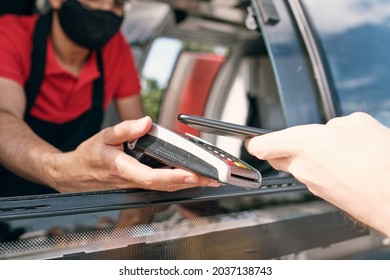 Seller Of Takeout Food Holding Payment Terminal In Window Of Truck While Client Paying For Snack