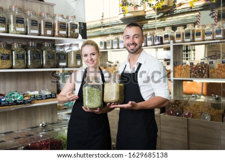 sellers posing with banks of dried herbs in store