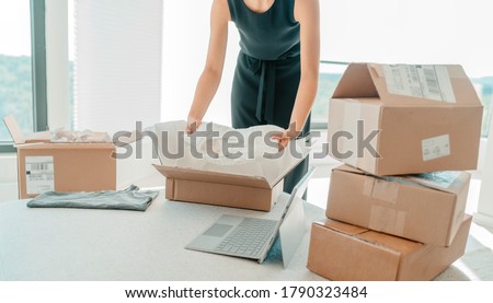 Selling clothing from home. Small business entrepreneur woman packing dress clothes in mailing box for shipping from online store.