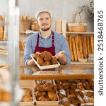 Selling fresh croissants in a bakery - Baker places hot croissants on display