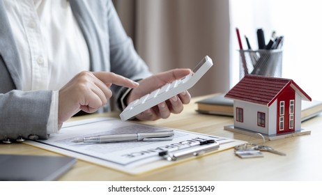 Selling a house with insurance, Salesperson or a home broker calculating the price to offer a special promotion and free insurance for customers who purchase a model home.