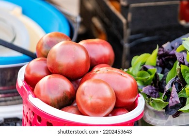 Selling Ripe Tomatoes And Basil At A Street Bazaar. Fresh Ripe Vegetables Grown On A Farm On A Small Counter