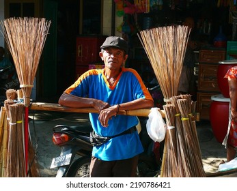 Semarang, Indonesia November 11th 2011 : 
Old Man Selling Bamboo Stick Brooms Using His Bicycle, Sunlight Shining On His Face Against A Blurred And Dark Background