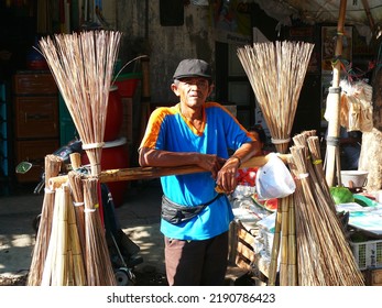 Semarang, Indonesia November 11th 2011 : 
Old Man Selling Bamboo Stick Brooms Using His Bicycle, Sunlight Shining On His Face Against A Blurred And Dark Background