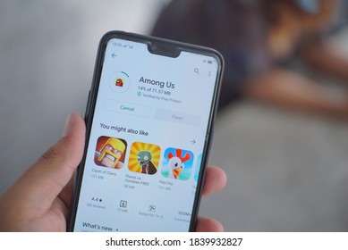 Semarang, Indonesia - October 24 2020: Close up of a hand holding a smartphone that installing among us game from play store. Installing among us.