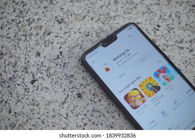 Semarang, Indonesia - October 24 2020: Close up of a hand holding a smartphone that installing among us game from play store. Installing among us.