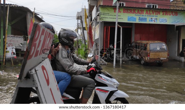 Semarang,Central Java/Indonesia - 09 April 2019\
: the driver and the community broke through the flood on the\
streets of\
Semarang