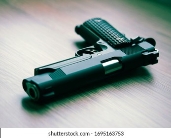 Semi automatic .45 ACP caliber pistol on wooden desk. Shallow depth of field