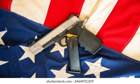 A semi automatic handgun with an additional loaded magazine is exhibited on an American flag in support of the 2nd Amendment