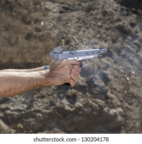 Semi automatic handgun loading another round while brass flies