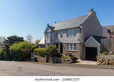 Semi detached house with a garage and featuring weather boarding against a clear blue sky