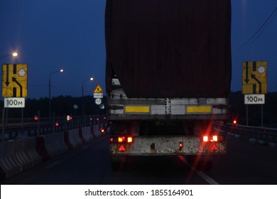 Semi Trailer Truck Move On Dry Asphalted Night Road Repair In Dark, Back View - Night Driving Safety