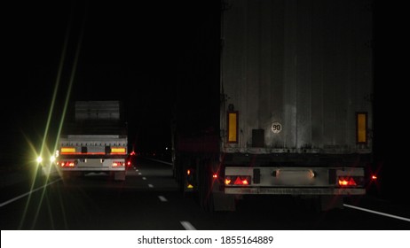 Semi trailer trucks move on dry asphalted night road in dark, back view - intrenational transportation logistics