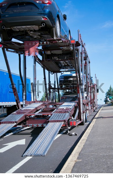 Semi Truck car hauler for transportation of\
cars on two-level trailer unloading trucks with decomposition\
runners for departure in anticipation of the continuation of the\
ongoing unloading