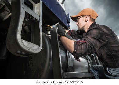 Semi Truck Driver In His 40s Checking Vehicle Elements Near Fuel Tank. Heavy Duty Transportation Theme.