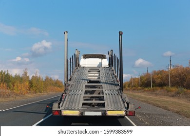 Semi Truck With Empty Car Carrier Trailer Running On The Road In Sunny Autumn Day.back View.car Transporter.transport Concept,work Of Heavy Truck Drivers.