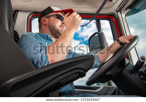 Semi Truck\
Lorry Driver Talking on CB Radio While Driving in Modern Semi\
Trailer Truck. Transportation Industry\
Theme.