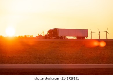semi truck on a road. sunset and wind turbines. Indiana, USA