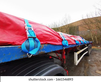 Semi Truck Trailer with a Tarp Covering the Steel Cargo, showing Close up of the Side of the Trailer with Blue Ratchet Straps Coiled up and Securing the Load underneath. - Shutterstock ID 1661546893