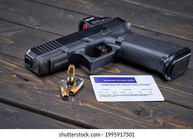 Semi-automatic Handgun With 9mm Self-defense Ammo Sitting On Wood Table Next To Concealed Weapon Permit                       