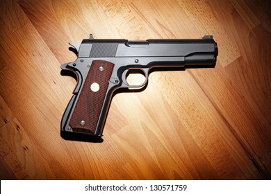 Semi-automatic M1911 Mark IV Series 80 .45 caliber pistol on the wooden table.