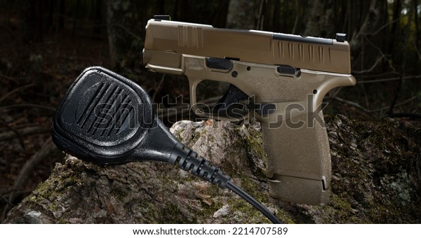 Semi-automatic pistol and two way radio microphone\
in a forest at\
dusk