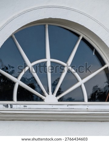Semicircular fanlight window featuring a sunburst design on a white building exterior