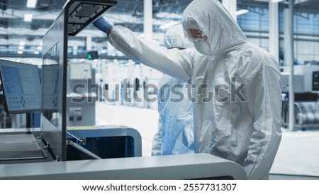Semiconductor Production Process At Electronics Factory: Two Technicians In Sterile Suits Taking Out Silicon Wafer From Soldering Jet Printer And Checking It. Engineers Creating Hardware For Computers