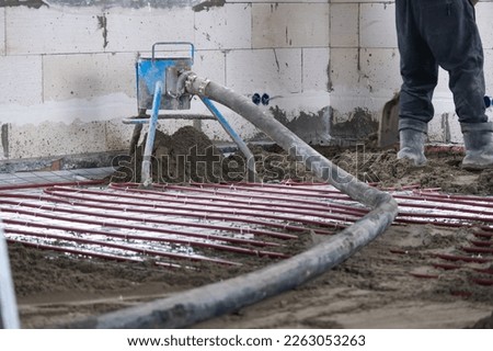 Semi-dry floor screed - a worker shovels a construction mixture through a special sleeve for cementing and leveling on underfloor heating pipes. Stock photo © 