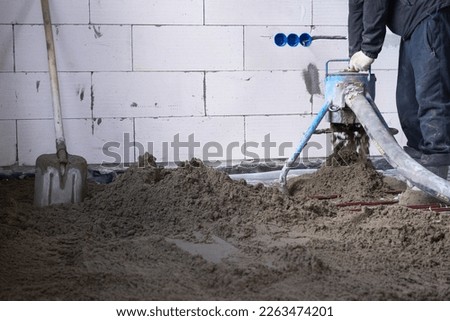 Semi-dry floor screed - a worker shovels a construction mixture through a special sleeve for cementing and leveling on underfloor heating pipes. Stock photo © 