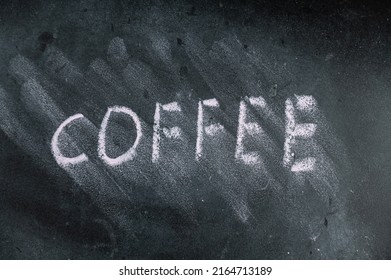 The Semi-erased Word COFFEE On Black Chalkboard. Handwritten Word. Fuzzy Letters On Black Surface.