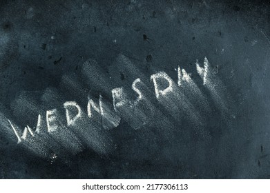 Semi-erased Word WEDNESDAY On Black Chalkboard. Handwritten Word. Fuzzy Letters On Black Surface. The Concept Of Alternating Days Of The Week. Calendar