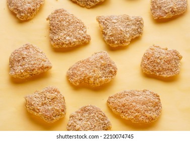 Semi-finished Products For Homemade Nuggets. Raw Frozen Pieces Of Breaded Chicken On A Yellow Background.