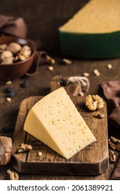 Semi-hard Aged Cheese With A Rich Taste With Nuts On A Wooden Board. Dark Wooden Background. Side View Close-up.