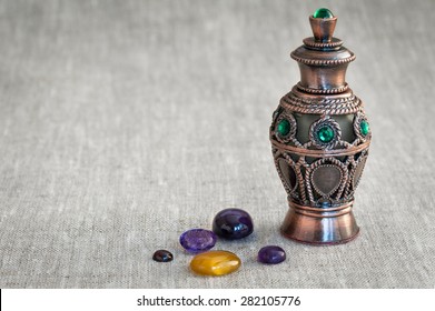 semi-precious stones and bottle of perfume on linen cloth