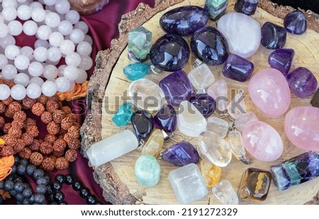 Semi-precious stones on the round saw cut tree trunk. Amethyst, rose quartz, agate, tiger's eye, malachite and citrine pendants.